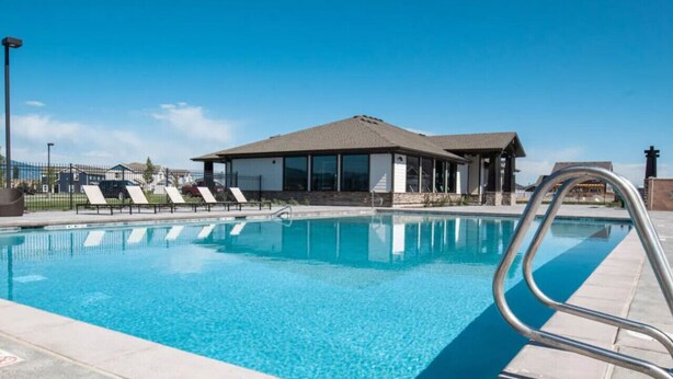 Una piscina con zona cubierta y sillones de descanso.