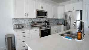 Una cocina moderna con armarios blancos, electrodomésticos de acero inoxidable, salpicadero de mármol y encimera de granito.