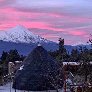 A pyramid-shaped building with a wooden staircase leading to a platform. - Casa Pumahue  (Puerto Varas)