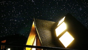 A building with a sloped roof and two illuminated windows. - Casa Pumahue  (Puerto Varas)