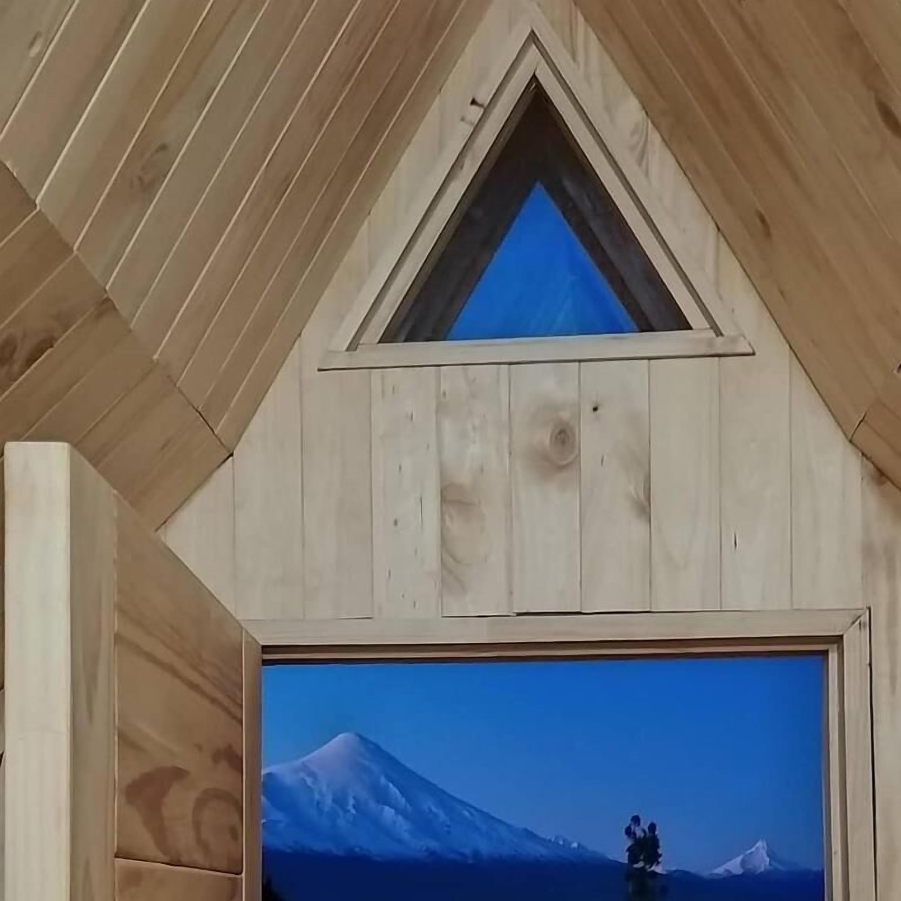 A room with wooden walls and a large window displaying a mountain view.