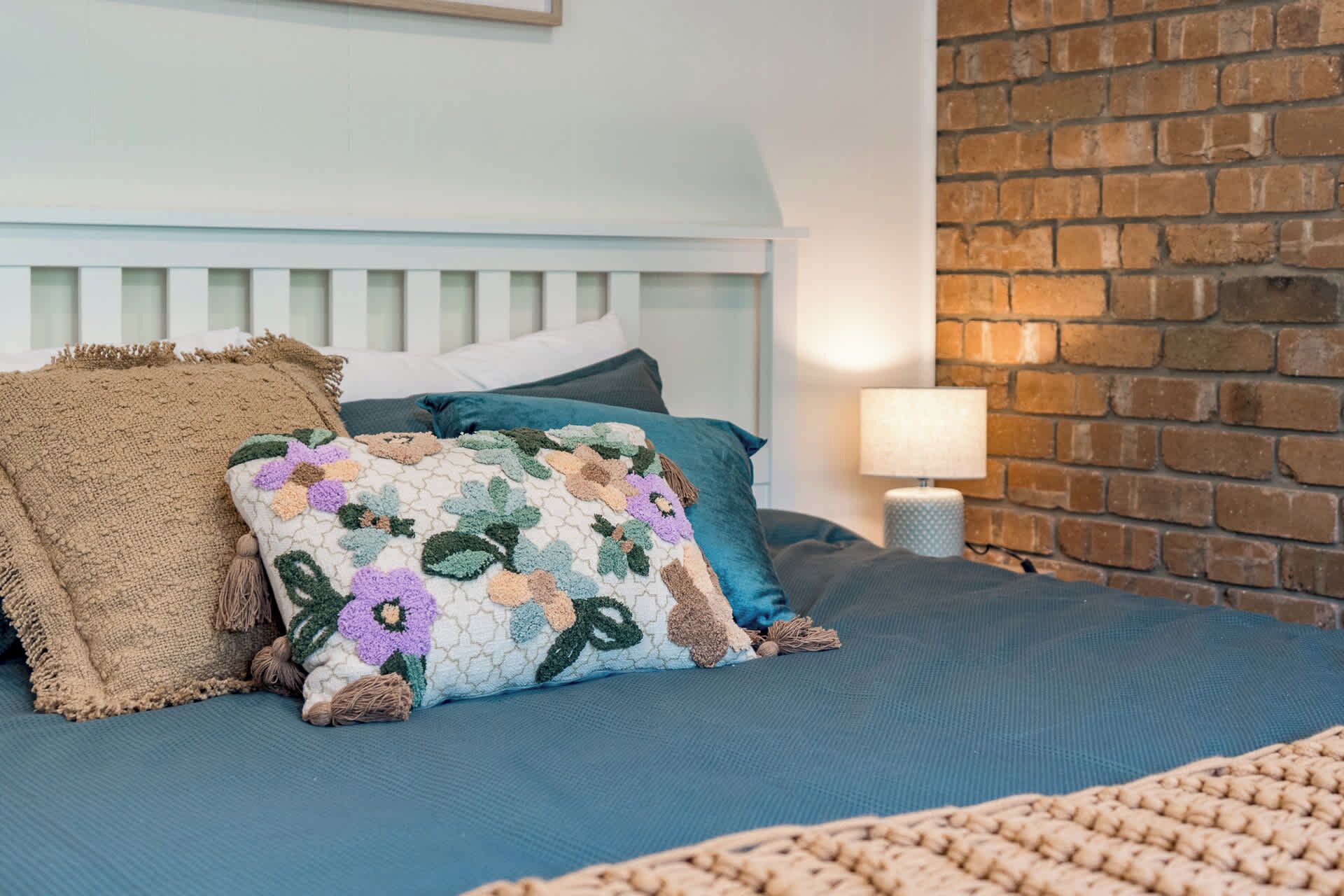 Un lit avec une tête de lit bleue, un oreiller à motifs et une couverture texturée.