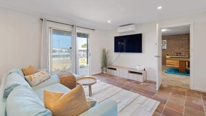 A living room with a sofa, TV, and a pool table in the background. - The Beach House 64 Neighbour Ave Goolwa Beach (Goolwa)