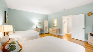 Ein Hotelzimmer mit zwei Betten, einem Schminktisch, einem Frisiertisch und einer Tür zu einem Badezimmer.