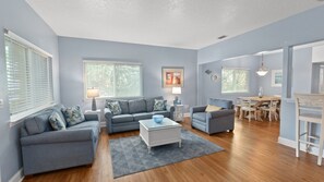 A living room with two sofas, a coffee table, and a dining area with a table and chairs. - Intracoastal Views + Dog-Friendly | Walk to Marina | Near Historic St. Augustine (St. Augustine)