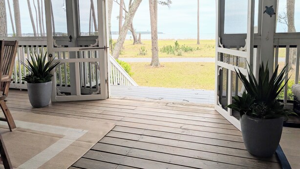 A covered porch with wooden flooring, white railings, and potted plants. - JonBie Maisons SEA GLASS COTTAGE cart included with booking (Daufuskie Island)