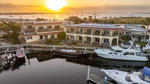 A marina with multiple boats docked, a waterfront building with balconies, and a sunset in the background. - Garden Studio | Sleeps 4 | Near Historic St. Augustine (St. Augustine)