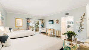 A hotel room with two beds, a desk, a TV, and a view of the outside. - Garden Studio | Sleeps 4 | Near Historic St. Augustine (St. Augustine)