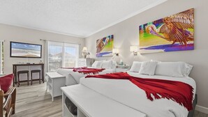 Ein Hotelzimmer mit einem großen Bett, einem Schreibtisch, einem Sessel und einem Fernseher.