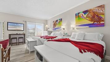 A hotel room with a large bed, a desk, a chair, and a TV.