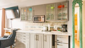 A modern kitchen with a microwave, coffee maker, and cabinets.