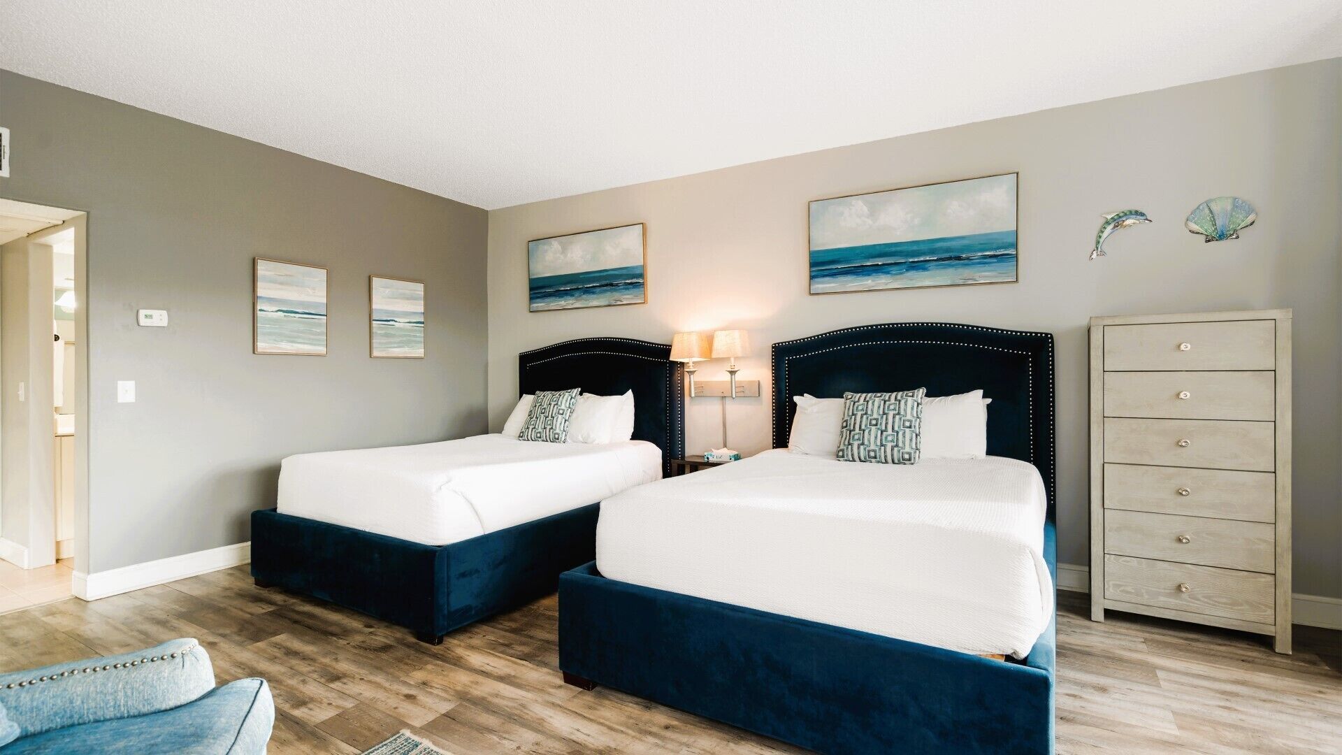 A hotel room with two beds, a dresser, and artwork on the walls.