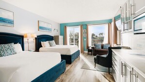 A hotel room with two beds, a dining area, and a view of the outdoors.