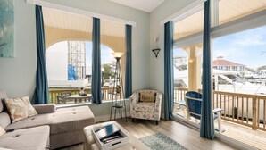 Ein geräumiges Wohnzimmer mit großem Fenster, einem Balkon und Blick auf Boote und einen Kran.