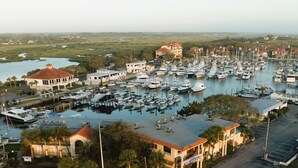 A marina with numerous boats docked, a building with a red roof, and a view of the surrounding landscape.