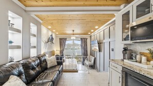 A modern kitchen with a marble countertop, a black leather sofa, and a view of the marina through large windows. - Harbor View Studio | King Bed + Covered Balcony | Dogs OK (St. Augustine)