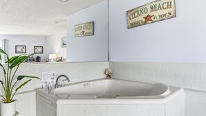 A bathroom with a white bathtub, a sink, and a mirror. There are two framed certificates on the wall and a sign that reads "Vilano Beach".