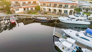 En lysthavn med flere både i havnen, en bygning med balkoner og en rolig vandoverflade.