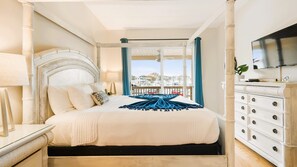 Relax in a classic hotel room with a large bed, flat-screen TV, and balcony overlooking the marina.
