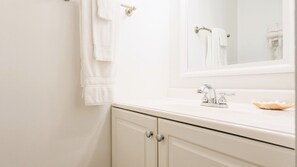 Une salle de bain avec un lavabo blanc, un miroir et un porte-serviettes.