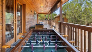 Un pontile in legno con un tavolo da calcio balilla, un divano e una ringhiera.