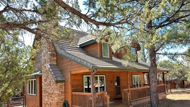 Un rustico chalet con fondamenta in pietra, rivestimento in legno e un portico con ringhiere.