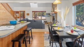 Una cucina moderna con una scala in legno, un'area pranzo con tavolo apparecchiato per quattro persone e un'ampia finestra vista all'esterno.