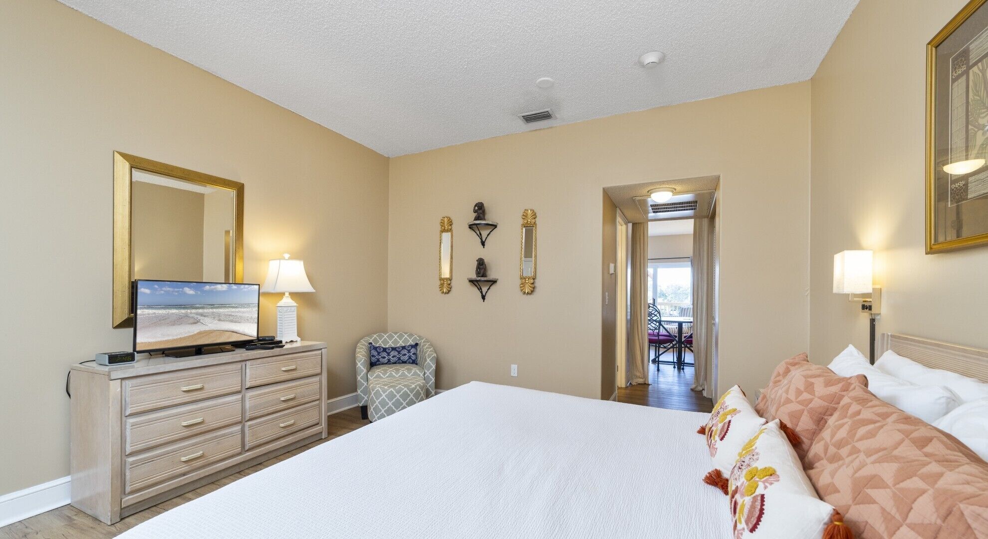 A hotel room with a large bed, a dresser, a television, and a desk.