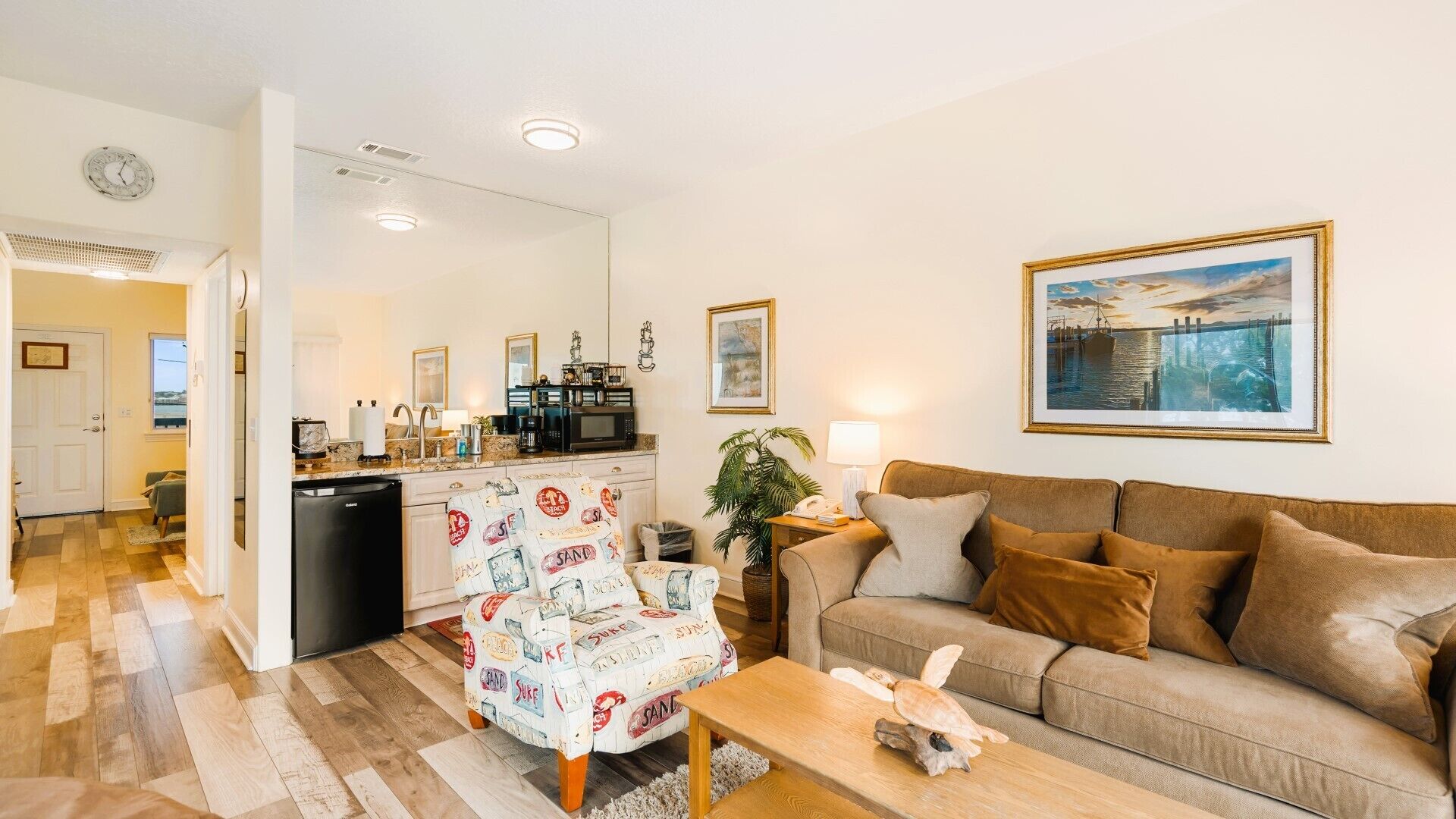 A living room with a sofa, a patterned armchair, a coffee table, and a painting on the wall.