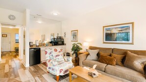 A living room with a sofa, a patterned armchair, a coffee table, and a painting on the wall. - History Meet Beach! King Studio, Sunroom and Balcony (St. Augustine)