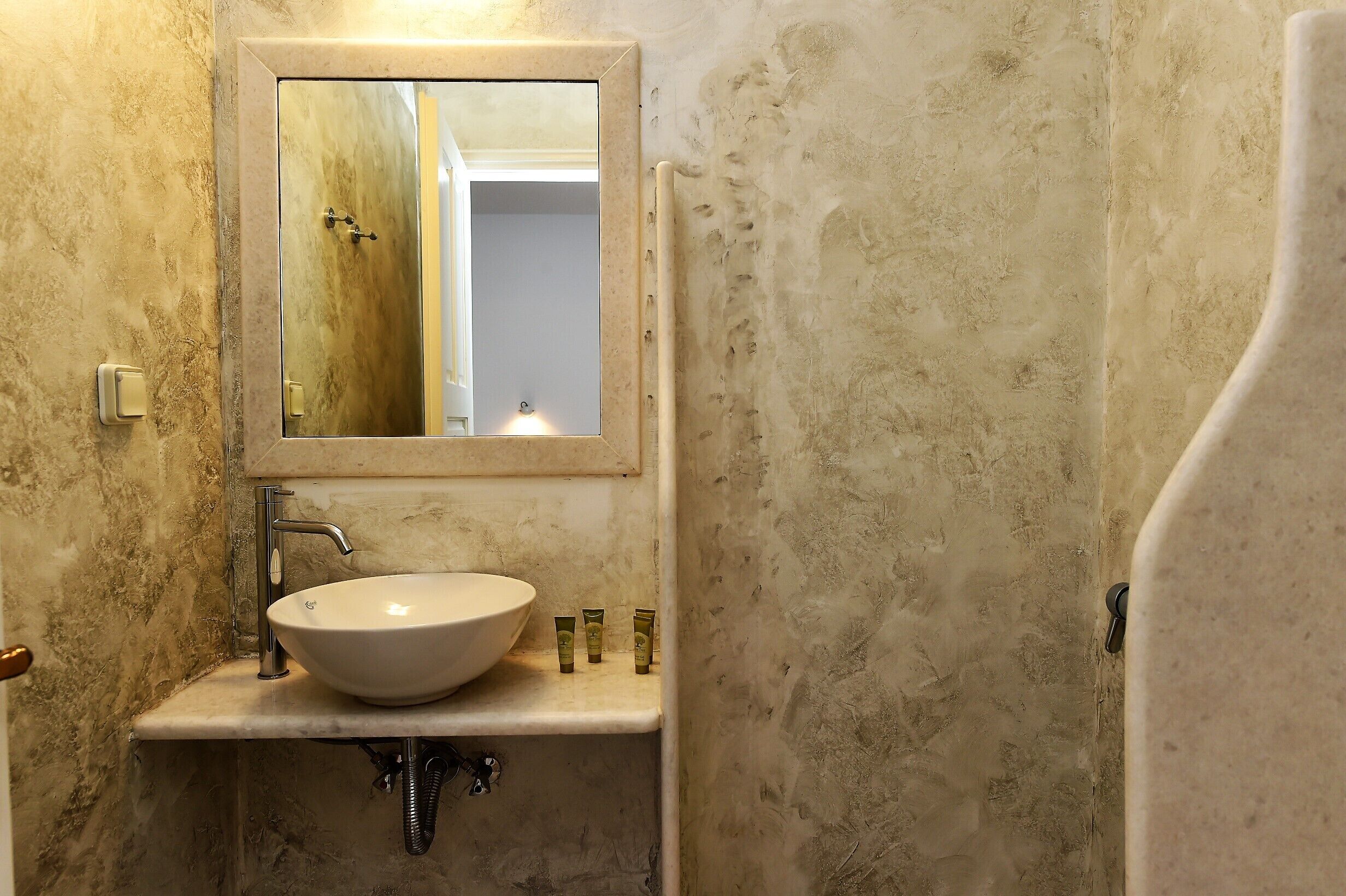 Un baño con lavamanos de mármol, un espejo y una ducha.