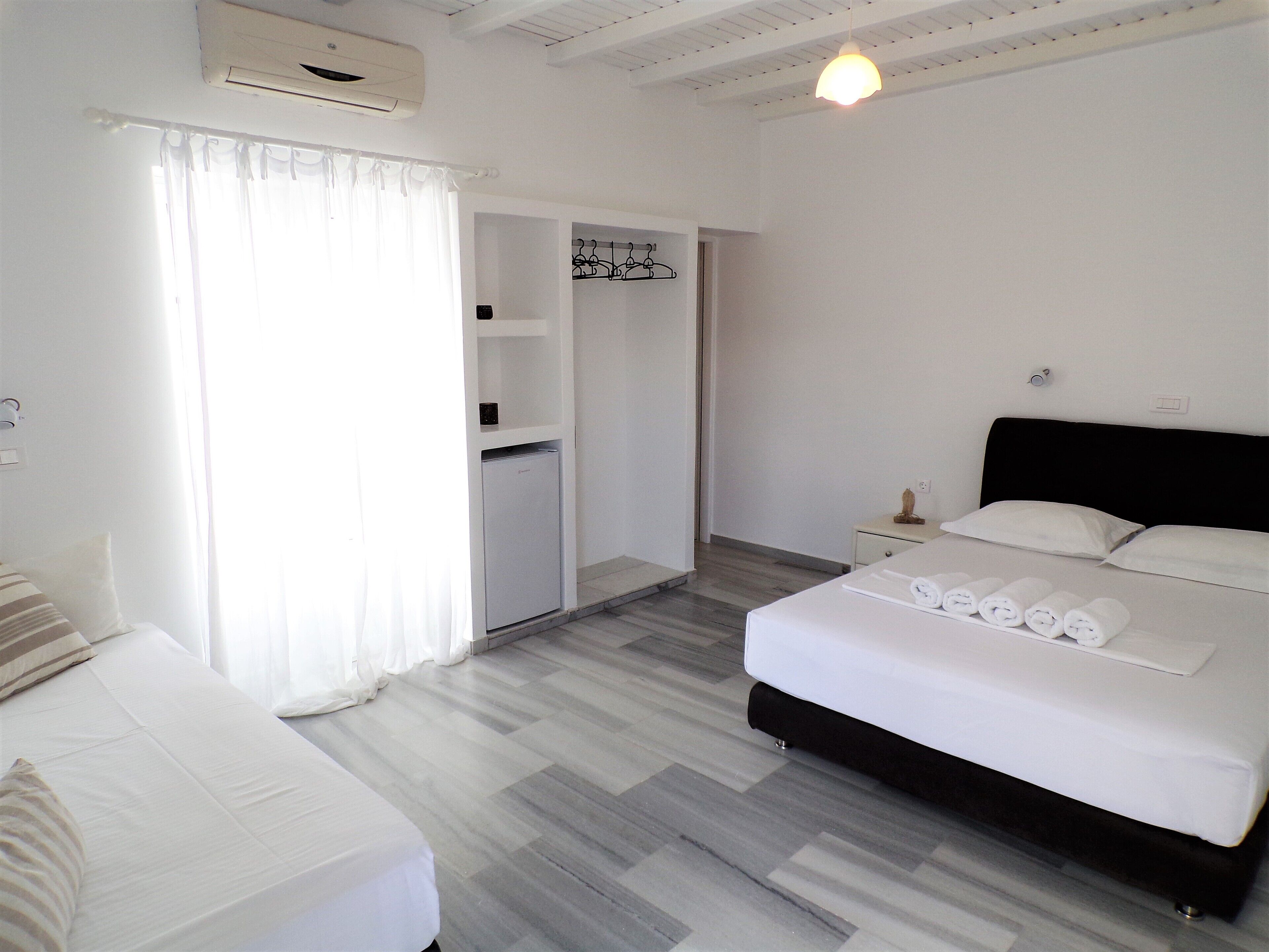 A hotel room with a bed, a bedside table, a wardrobe, and a small table with towels.