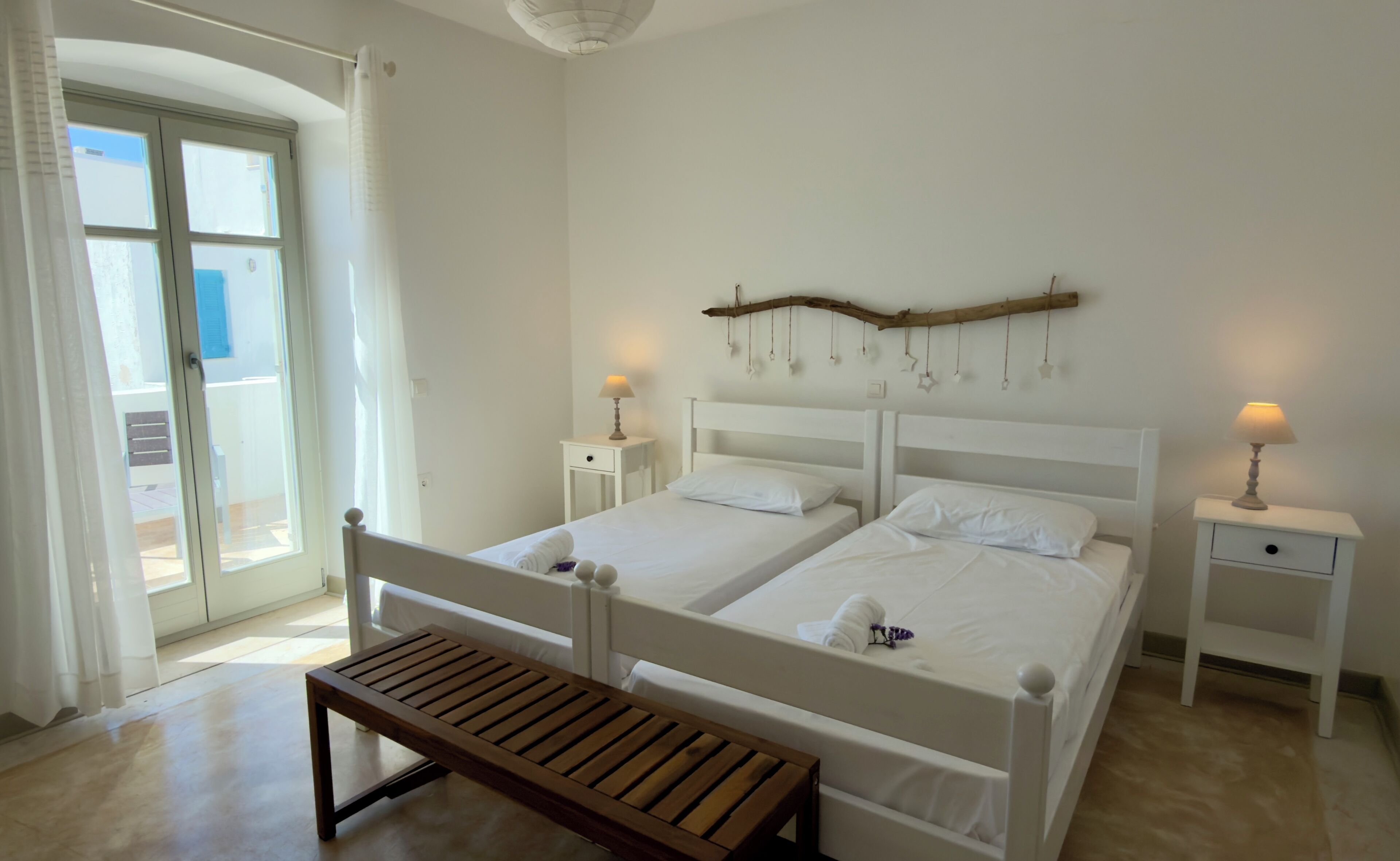 Un dormitorio con dos camas, un banco y un adorno de pared de madera.