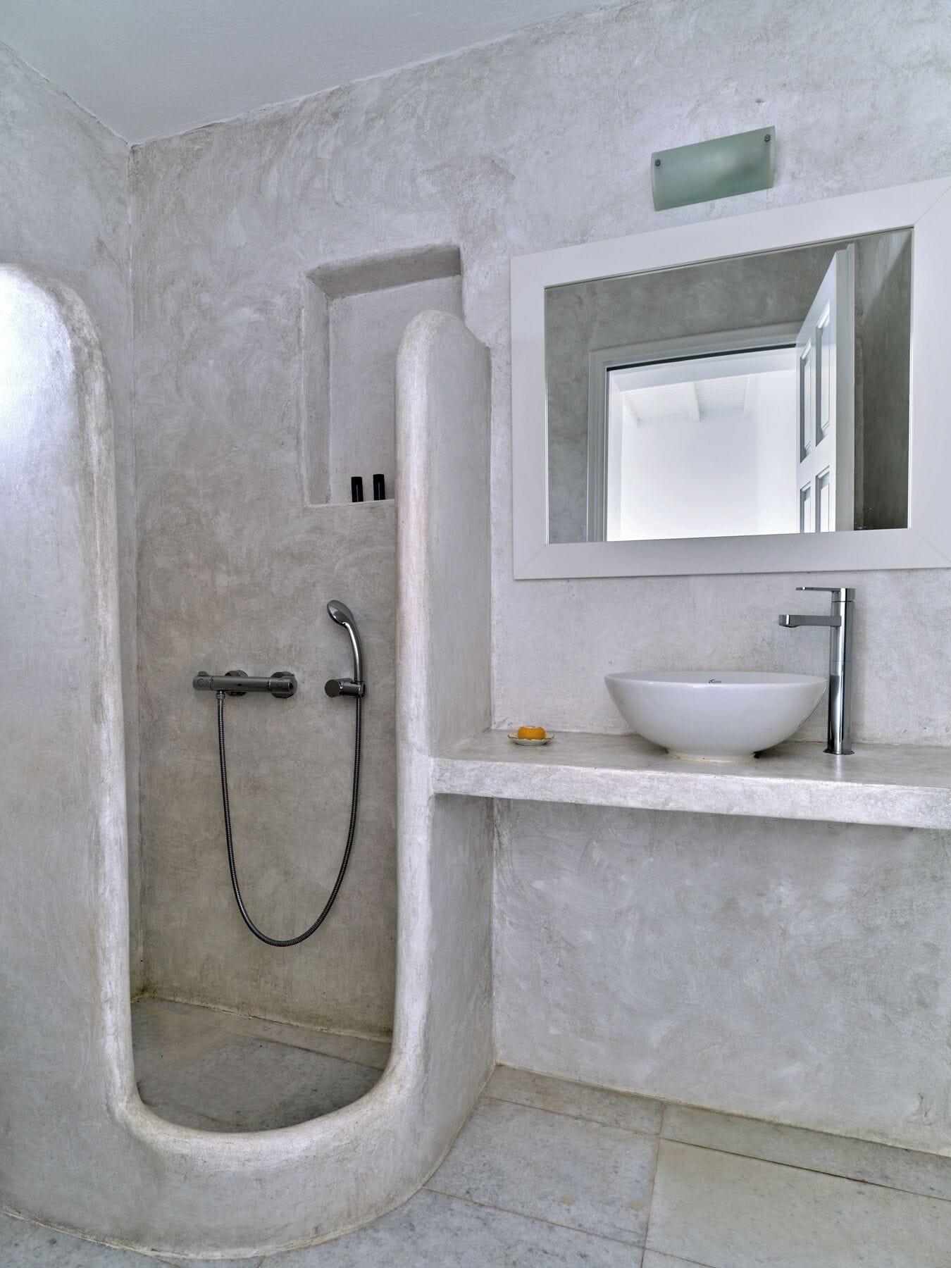 Un bany modern amb plat de dutxa, un lavabo blanc i un mirall sobre el lavabo.