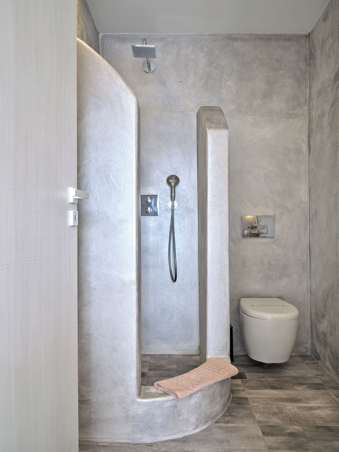A modern bathroom with a walk-in shower, a toilet, and a towel rack.
