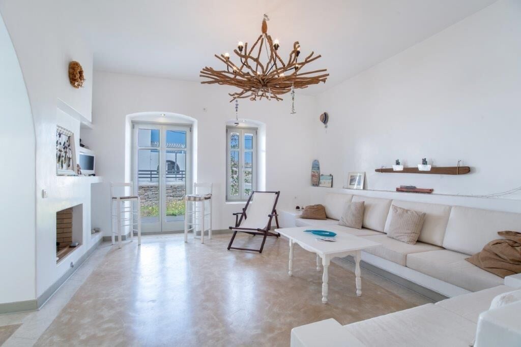 A spacious living room with a white sofa, a coffee table, a wooden chair, and a chandelier.