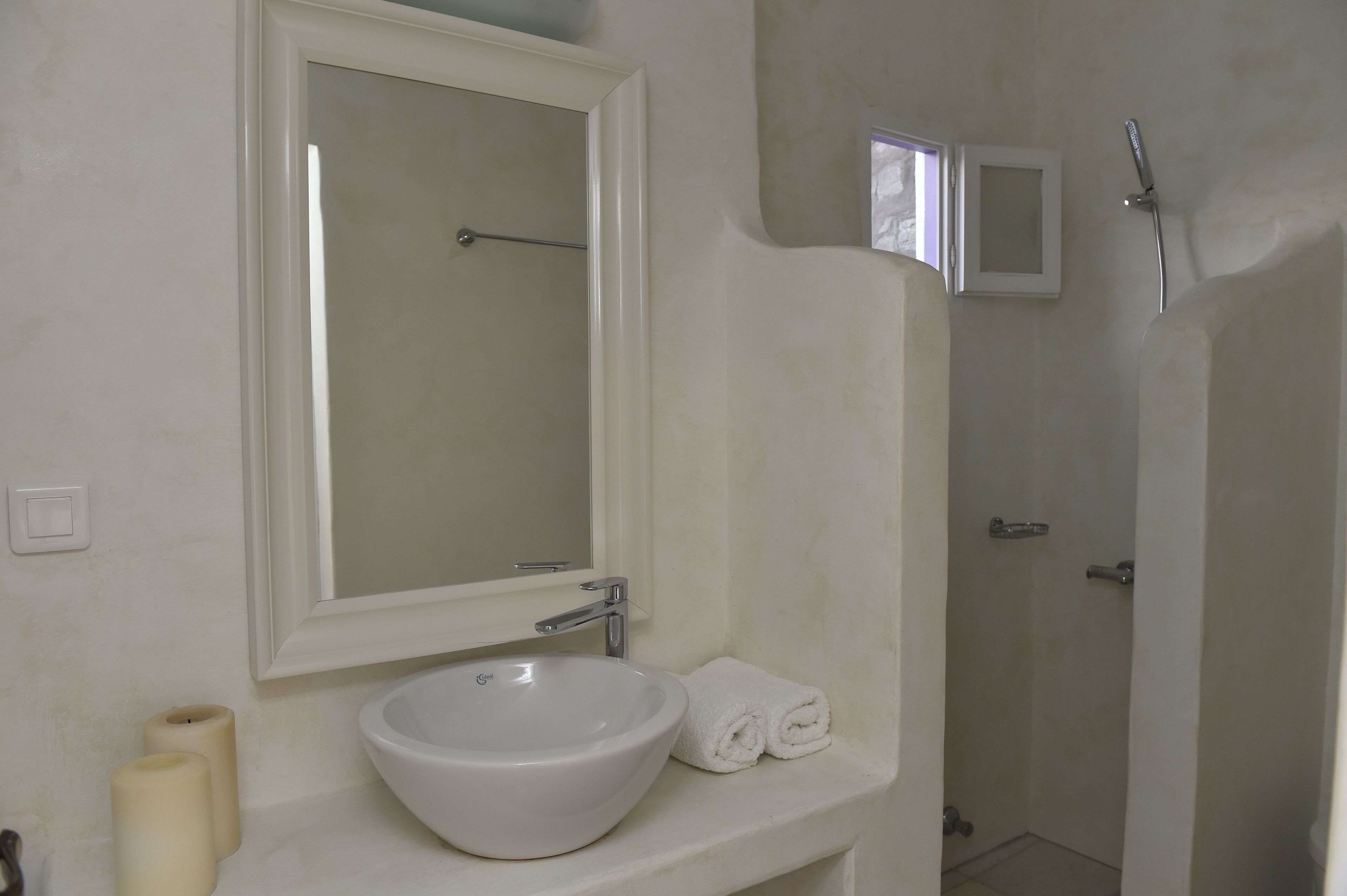 A bathroom with a white sink, a mirror, a towel, and a shower.