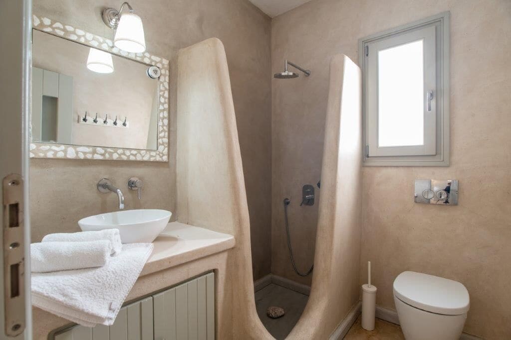 A bathroom with a sink, mirror, towel rack, shower, and toilet.