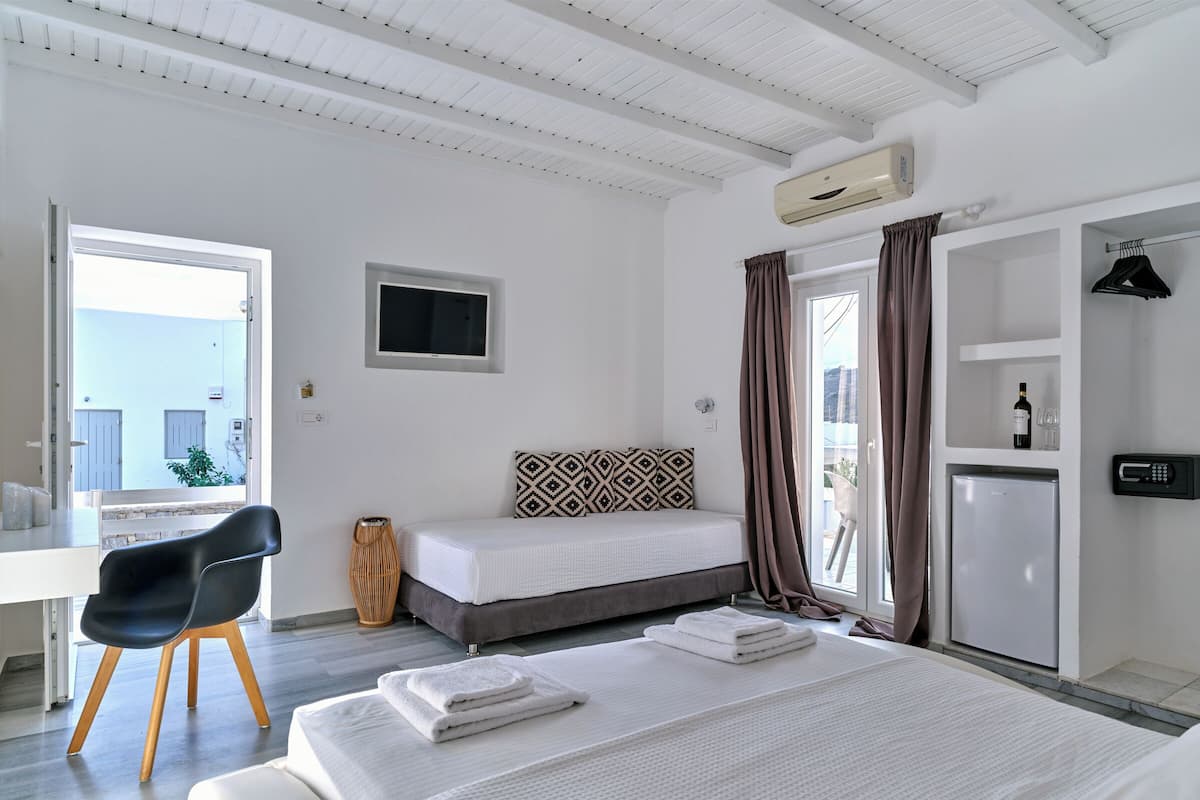 A hotel room with a bed, a desk, a chair, a wardrobe, and a window with curtains.
