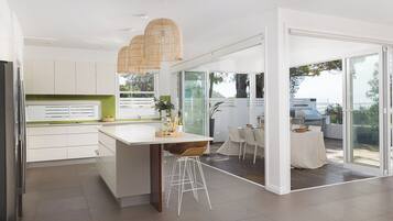 A modern kitchen with white cabinets, a central island, and a dining area with a table and chairs.