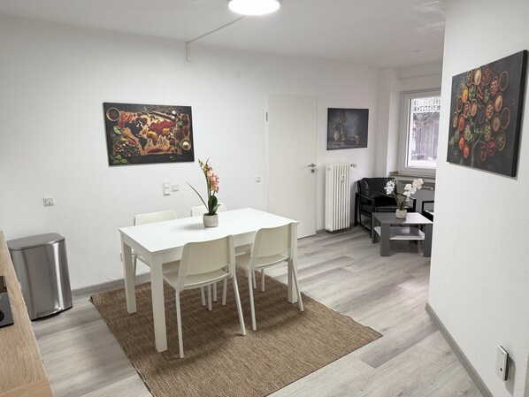 A modern dining area with a white table and chairs, a small potted plant, and artwork on the walls. - #1 Top room: central & comfortable, shared bathroom (Bochum)