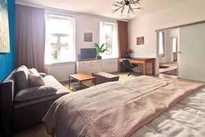 A bedroom with a bed, a desk, a chair, a sofa, and a window. -  Blue Palm - 60m2 - cozy, central with a green view (Vienna)