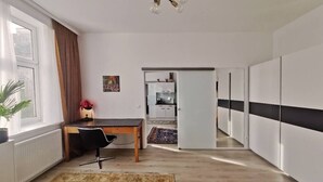 Een moderne woonkamer met een eethoek, een keuken op de achtergrond en een gang naar een inloopkast.
