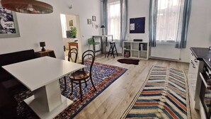 Een moderne woonkamer met een eethoek, een keuken en een groot raam met gordijnen.