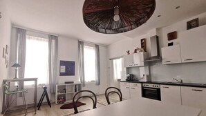 Een moderne keuken met witte kasten, een eettafel en een grote plafondventilator.