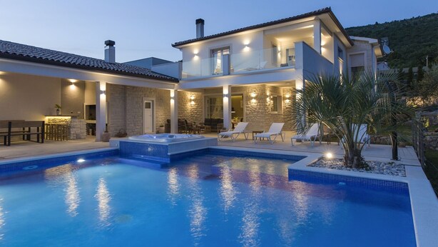 Une maison à deux étages dotée d’une piscine, d’un espace salon extérieur et d’un jacuzzi.