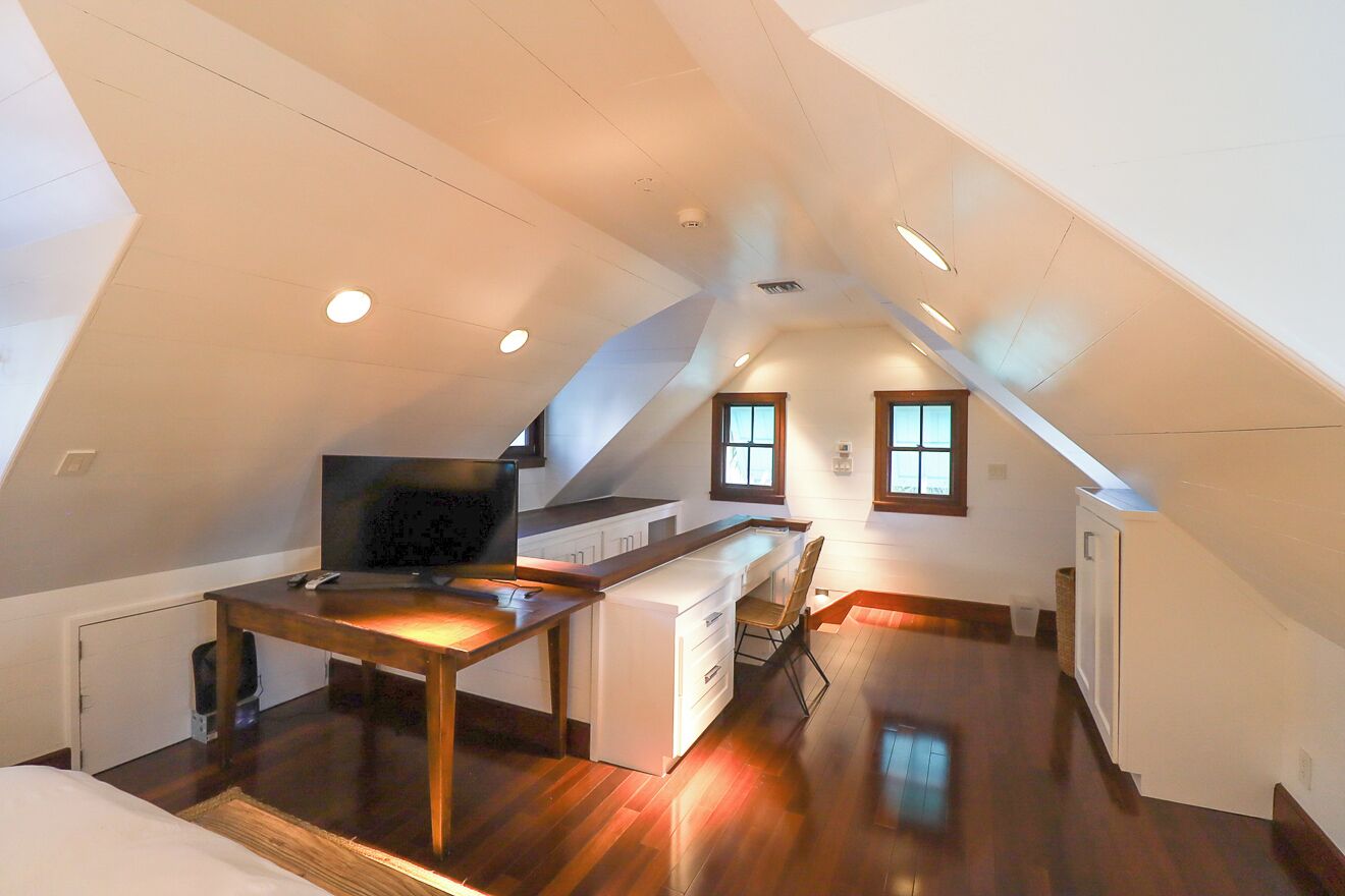 Quarto estilo loft moderno, com uma janela grande, escrivaninha embutida e um espaço de estar acolhedor.