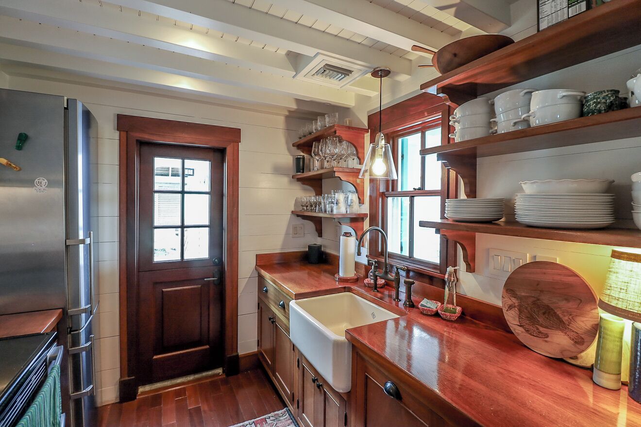 A kitchen with wooden cabinets, a stainless steel refrigerator, a sink, and a window with a view.