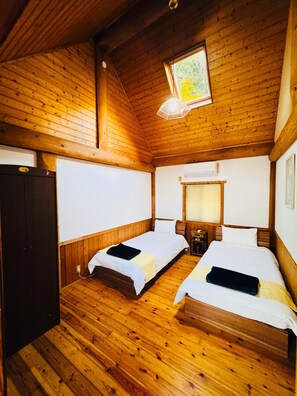 A cabin with two wooden beds, a wardrobe, and a window with a view of trees. - Yufuin Tom Sawyer (Yufu)