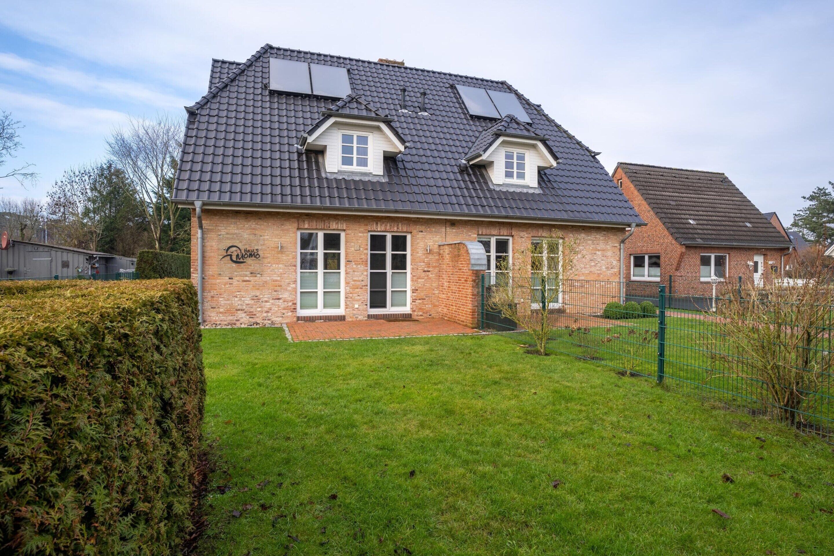 A two-story house with a brick exterior, a tiled roof, and two skylights.